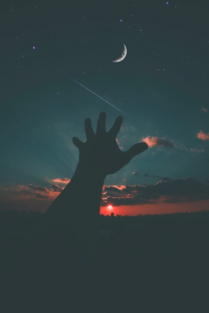 dans la nuit une main s'élève vers le ciel et la lune